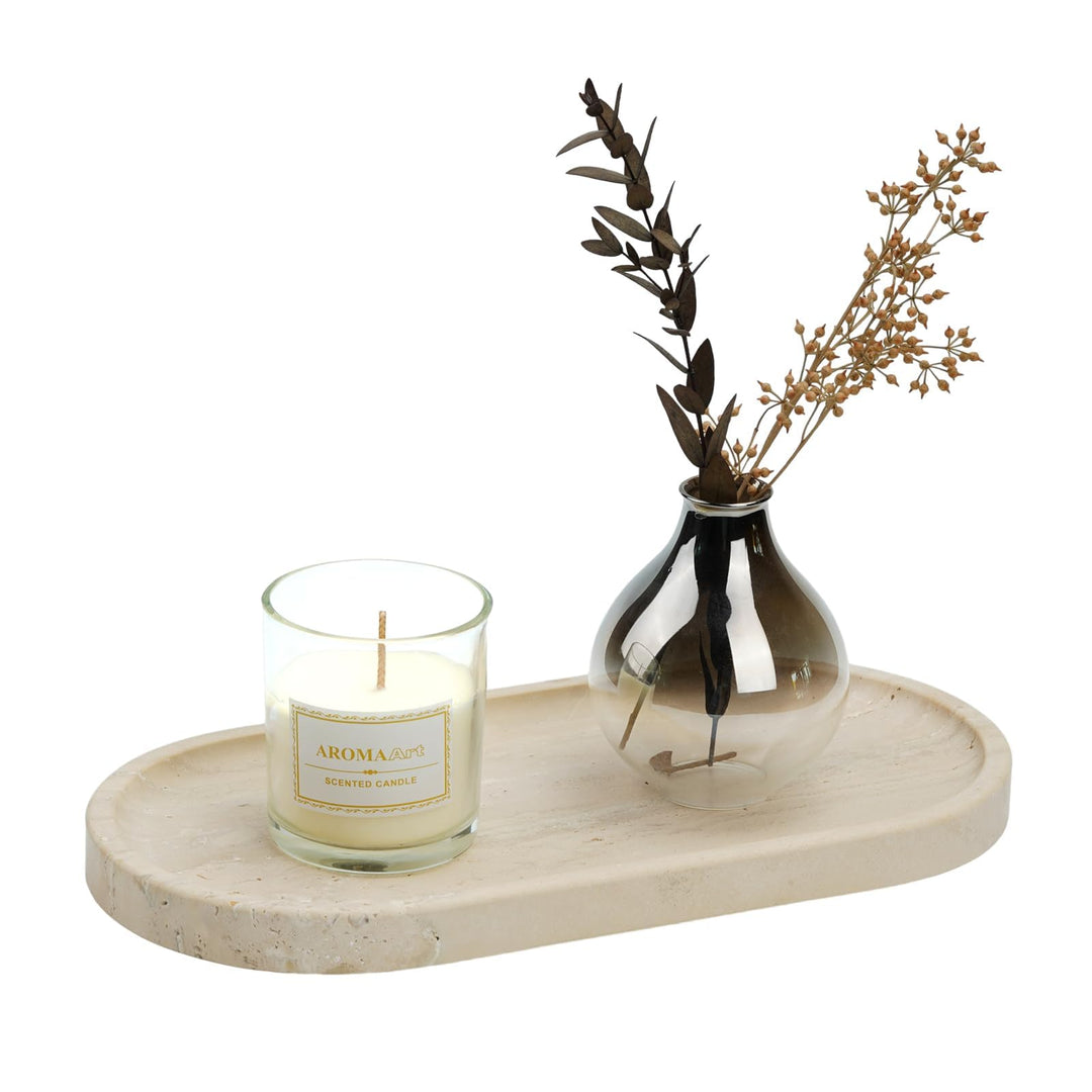 Light beige travertine tray with rounded ends holding a candle and a smoked-glass bud vase with dried stems