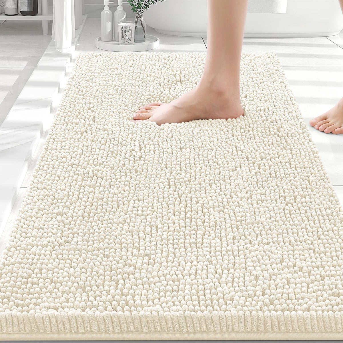 Ivory Smiry chenille bath mat on a bathroom floor as bare feet step onto the plush pile