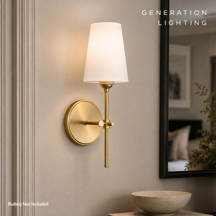 Satin brass Baker sconce lit beside a dark-framed mirror above a stone bowl