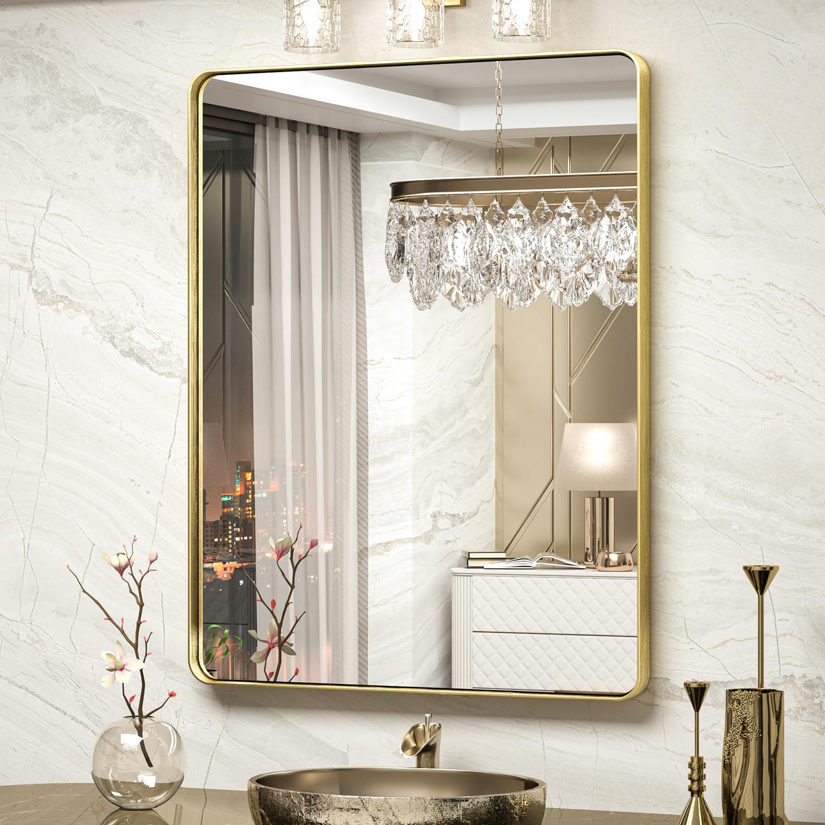 Brushed gold rectangular mirror with rounded corners on a white marble wall above a vessel sink